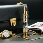 An opulent vaping device embellished with gold, alongside a designer handbag and luxury fashion items, conveying a blend of style and elegance.